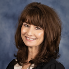 headshot of a smiling brown-haired woman wearing business professional clothing