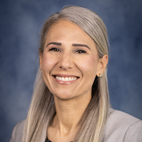 headshot of a smiling woman with light hair dressed in a grey suit